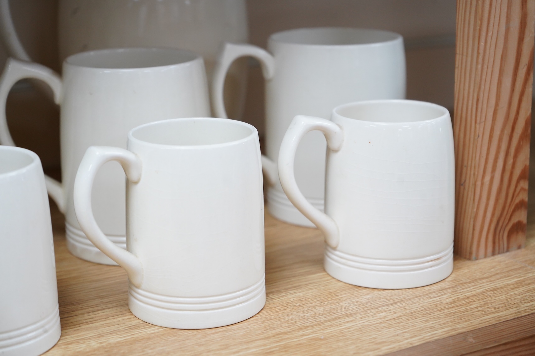 Keith Murray for Wedgwood, a cream lemonade jug, five small mugs, two large three faceted, largest 21cm high (12)